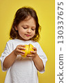cute funny little child girl holding lemon on yellow background 130337675