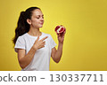 Beautiful happy woman holding pomegranate on yellow background 130337711