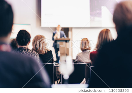 Speaker giving a talk in conference hall at business event. Rear view of unrecognizable people in audience at the conference hall. Business and entrepreneurship concept 130338293