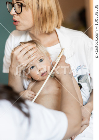 Small child being checked for heart murmur by heart ultrasound exam by cardiologist as part of regular medical checkout at pediatrician 130338339