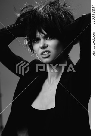 Black and white portrait of an expressive woman with messy hair and intense emotion in studio lighting 130338834