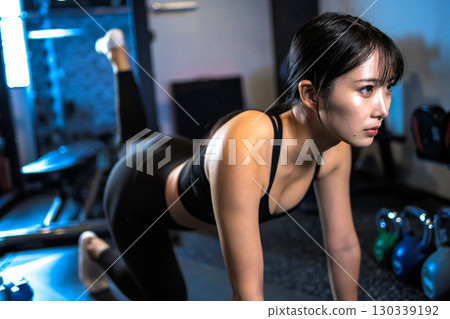 Cool woman training her buttocks with back kicks, muscle training, hip up, sports gym Cool woman training her buttocks with back kicks, muscle training, hip up, sports gym 130339192