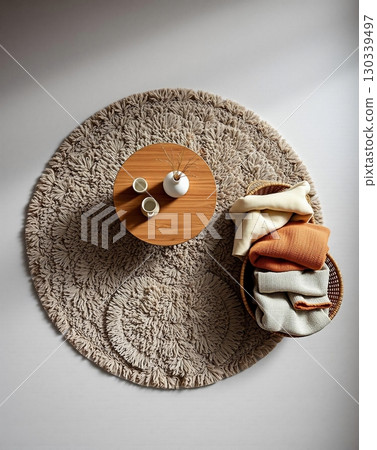 Cozy Home Decor: Round Rug, Wooden Table with Vase, and Basket of Blankets Cozy Home Decor: Round Rug, Wooden Table with Vase, and Basket of Blankets 130339497