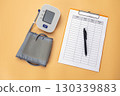 Blood pressure monitor with a data recording pad and pen is placed on the table, showing that it is a practice of self care by recording daily health data. 130339883