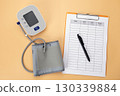 Blood pressure monitor with a data recording pad and pen is placed on the table, showing that it is a practice of self care by recording daily health data. 130339884