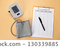 Blood pressure monitor with log pad and pen on table, showing hypertension care through daily self tracking of health data. 130339885