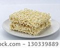 Uncooked instant noodle dry ramen block wavy pasta square brick white plate simple food closeup studio lighting minimal style beige color fill calm mood with clean composition and soft texture 130339889