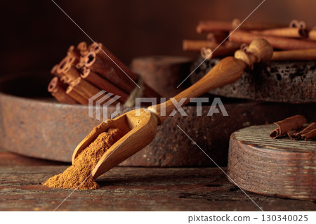 Wooden spoon with cinnamon powder and cinnamon sticks. Wooden spoon with cinnamon powder and cinnamon sticks. 130340025