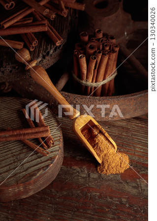 Wooden spoon with cinnamon powder and cinnamon sticks. Wooden spoon with cinnamon powder and cinnamon sticks. 130340026