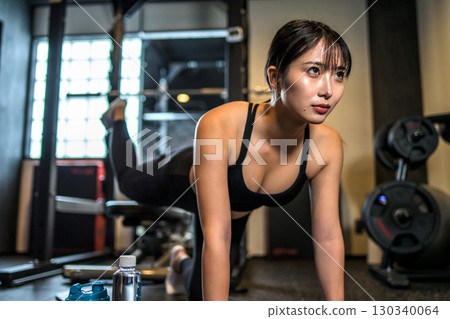 Cool woman training her buttocks with back kicks, muscle training, hip up, sports gym 130340064