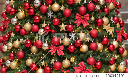 Christmas tree decorated with red, gold, and glitter ornaments, bows, stars and lights for festive holiday celebration 130340101