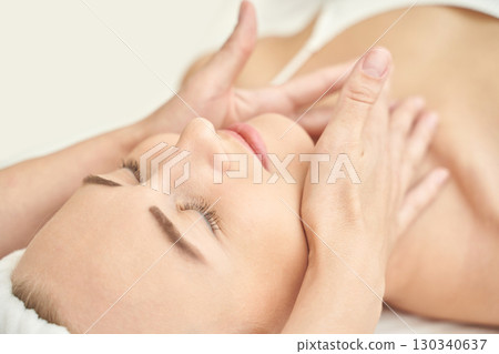 Caucasian female enjoying relaxing facial massage in spa setting with gentle 130340637