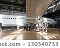 White passenger airplane in the aircraft hangar. Checking mechanical systems for flight operations. Plane under maintenance 130340733