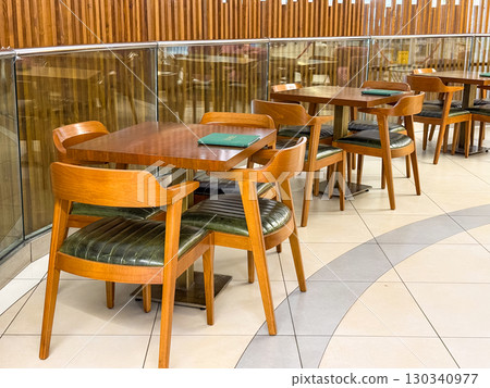 Wooden tables and chairs in a cafe. Dining, interior seating, and hospitality design. 130340977