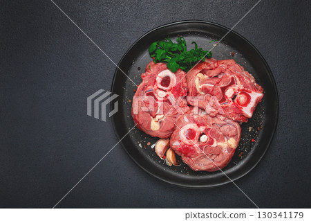 raw steak, calf's neck on the bone, fresh meat, on a black plate, top view, no people, 130341179