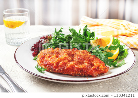 Milanese chicken, Crispy breaded chicken served, with fresh herbs, and lemon wedges, 130341211
