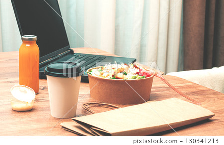 work at home on a laptop, there is food on the table, salad, coffee and juice, delivery, there are no people, work at home on a laptop, there is food on the table, salad, coffee and juice, delivery, there are no people, 130341213