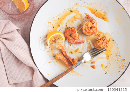 the remains of fried shrimp in oil with spices, on a white plate, with a fork, there are no people, 130341215