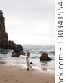 In Solitude by the Ocean A Woman Walking Alone Peacefully on the Beautiful Scenic Beachside 130341554