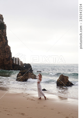 In Solitude by the Ocean A Woman Walking Alone Peacefully on the Beautiful Scenic Beachside 130341554