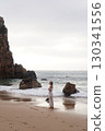 In Solitude by the Ocean A Woman Walking Alone Peacefully on the Beautiful Scenic Beachside 130341556