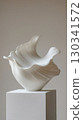 Vertical photo of smooth white ceramic shell-shaped vase with flowing organic curves 130341572
