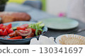 Woman eating at table in a Backyard. Outdoor lunch, barbecue. Garden party celebration in a backyard. Young people have fun, eat and drink sunny summer day. 130341697