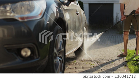 Man wash car with high pressure washer. Self-service manual car wash outdoors. Summer daytime. 130341718