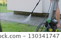 Young woman wash clean path with pressure washer in the backyard. 130341747