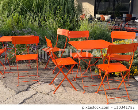 Red metal chairs and a tables on an outdoor cafe terrace. Street dining, casual atmosphere and everyday urban lifestyle. Red metal chairs and a tables on an outdoor cafe terrace. Street dining, casual atmosphere and everyday urban lifestyle. 130341782