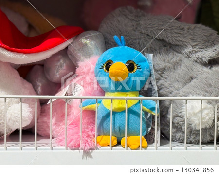 Plush bird toy with bright colors and shiny eyes on a shelf. Childhood, play, and consumer lifestyle through toys and retail experience. 130341856