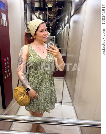 Woman taking a mirror selfie at home in a floral summer dress. Fashion, femininity and casual lifestyle in everyday surroundings. 130341917
