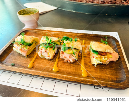 Sandwich portions with fresh vegetables on wooden tray. Culinary presentation, nutrition, and gourmet lifestyle in cafe dining experience. Sandwich portions with fresh vegetables on wooden tray. Culinary presentation, nutrition, and gourmet lifestyle in cafe dining experience. 130341961