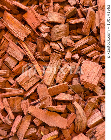 Red wood chips arranged as mulch creating a rough surface texture for landscaping and decoration. Organic recycling, natural material and environmental resource for gardening and ecological design. 130341962