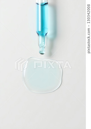 Droplet of blue serum suspended from pipette, skincare and cosmetic science concept Droplet of blue serum suspended from pipette, skincare and cosmetic science concept 130342008
