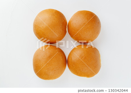 Top view of four fresh golden burger buns on white background, minimalistic bakery concept Top view of four fresh golden burger buns on white background, minimalistic bakery concept 130342044