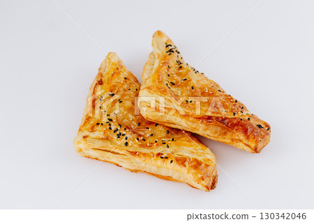 Golden puff pastry triangles with sesame seeds isolated on white background 130342046