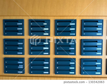 Row of numbered metal mailboxes installed on a wooden wall in residential building. Communication, infrastructure and housing facility representing organization, delivery and correspondence service. Row of numbered metal mailboxes installed on a wooden wall in residential building. Communication, infrastructure and housing facility representing organization, delivery and correspondence service. 130342063