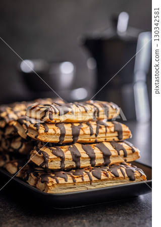 Sfogliatine glassate with chocolate. Italian crispy dessert on plate on black table. 130342581