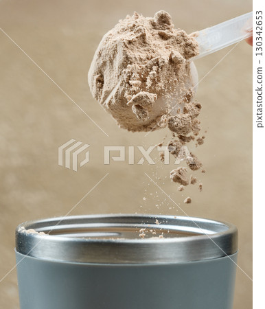 protein powder spills in cup from measure scoop. whey sports nutrition. dry mixture protein powder spills in cup from measure scoop. whey sports nutrition. dry mixture 130342653