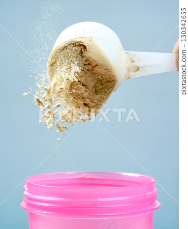 protein powder spills in cup from measure scoop. whey sports nutrition. dry mixture protein powder spills in cup from measure scoop. whey sports nutrition. dry mixture 130342655