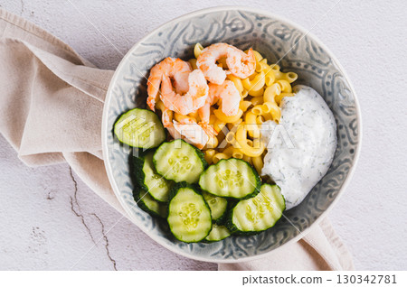 Close up of bowl with pasta, shrimp, cucumber and sauce on the table top view Close up of bowl with pasta, shrimp, cucumber and sauce on the table top view 130342781