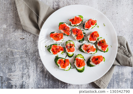 Close up of appetizing snack of cucumber, ricotta and red fish on a plate top view 130342790