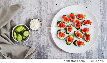 Cucumber appetizer with ricotta and salted red fish on a plate top view web banner 130342792