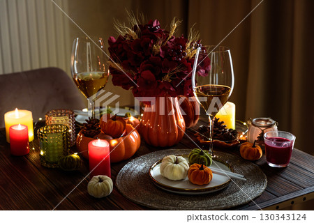 Thanksgiving table setting with decorative pumpkins, candles and string lights on dark wooden table Thanksgiving table setting with decorative pumpkins, candles and string lights on dark wooden table 130343124