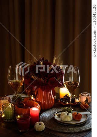 Thanksgiving table setting with decorative pumpkins, candles and string lights on dark wooden table Thanksgiving table setting with decorative pumpkins, candles and string lights on dark wooden table 130343126