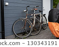Two old vintage bicycles leaning against gray wooden wall 130343191