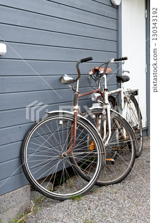 Two old vintage bicycles leaning against gray wooden wall Two old vintage bicycles leaning against gray wooden wall 130343192