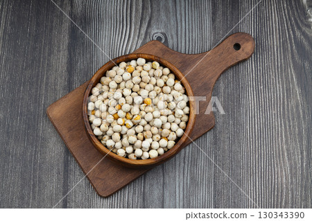 Roasted white chickpeas in wooden bowl on wooden background, top view. White chickpeas, with their high fiber content, are very healthy to consume. 130343390