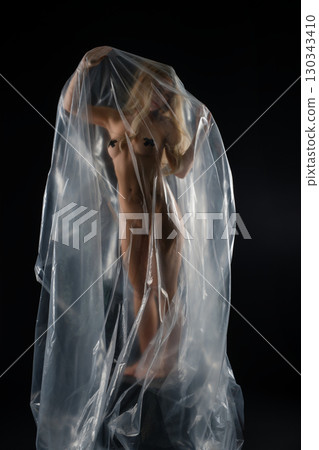 Studio portrait of a blonde woman artistically draped in transparent material Studio portrait of a blonde woman artistically draped in transparent material 130343410